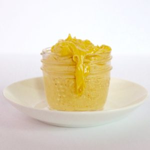 a small mason jar filled with yellowy hollandaise sauce, a drip coming over the side