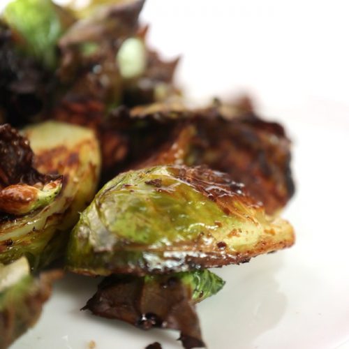 a white plate with crispy fried brussels sprouts with crispy brown bits