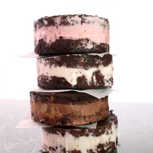 A stack of round ice cream sandwiches with a chocolate cookie and various kinds of ice cream filling